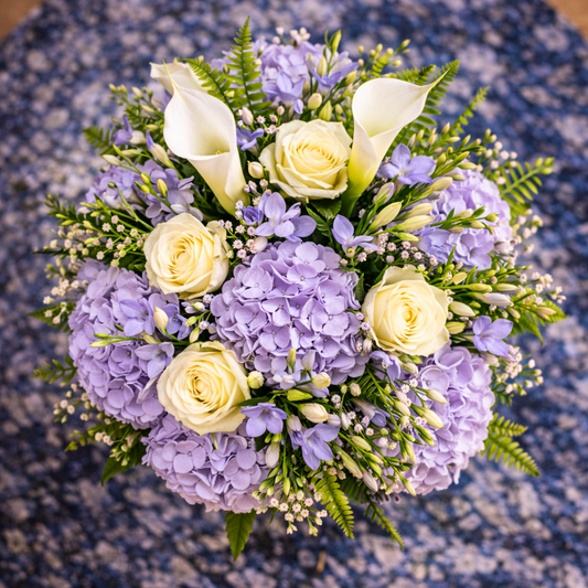 Bouquet of purple and white flowers on a textured blue surface