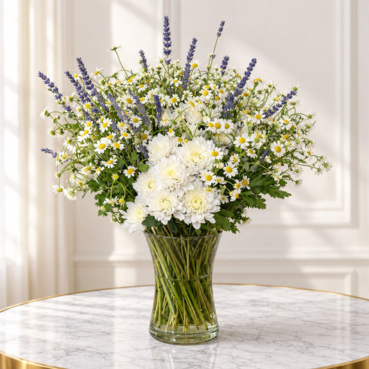 Chamomile flower arrangement with white chrysanthemums and purple lavender stems in a clear glass vase