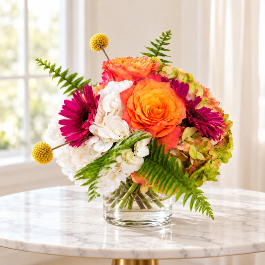 Colorful flower centerpiece with coral roses, fuchsia gerberas and white hydrangeas