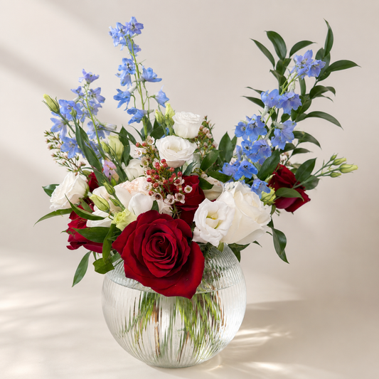 Modern floral centerpiece Toronto featuring premium white flowers, blue delphiniums, and red roses by Amarilis Flowers.