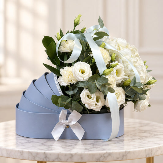 New baby flowers Toronto arrangement with white roses and hydrangeas in a powder-blue bassinet