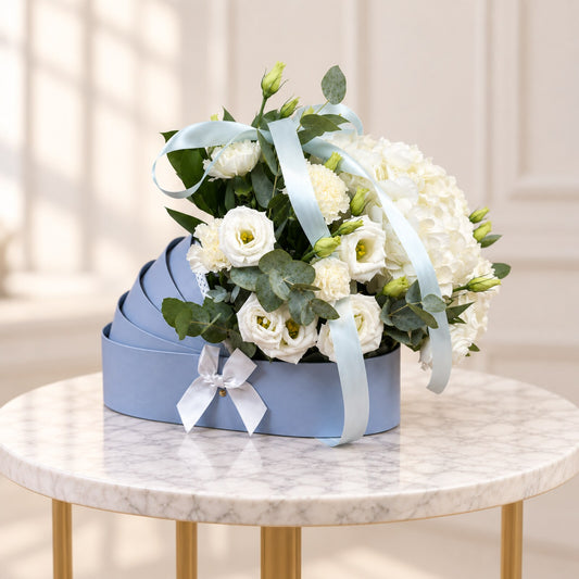 Tender Beginnings newborn gift with white flowers, eucalyptus and a silver satin bow