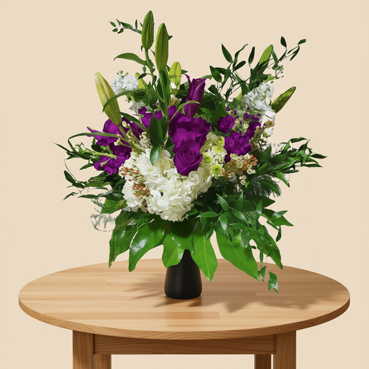 Garden-style floral arrangement with purple flowers in glass vase