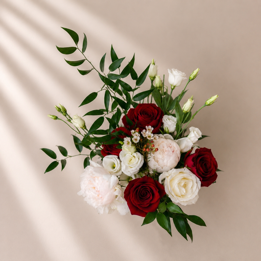 Bouquet of red and white flowers with green leaves on a beige background