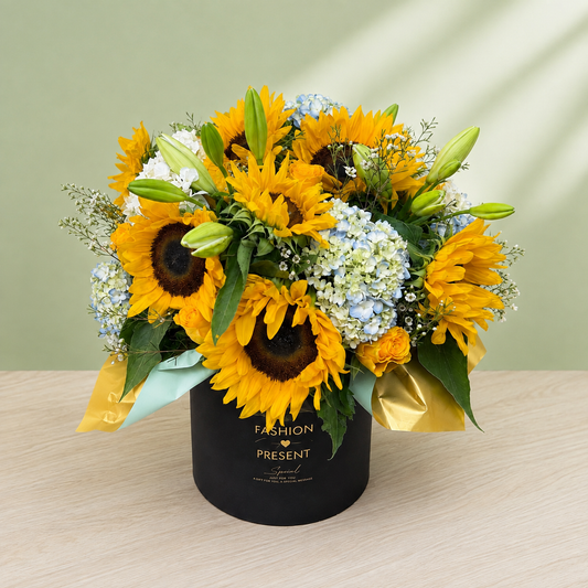 Angled view of the Sunlit Garden sunflower arrangement in a black box with gold and pale-blue accents
