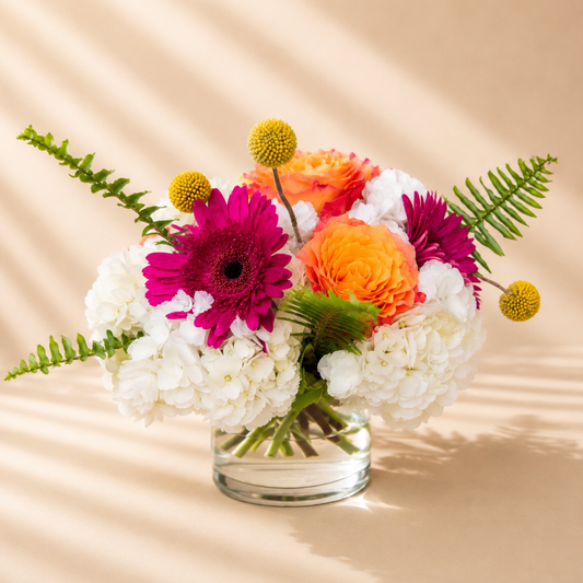 Vibrant floral centerpiece with orange roses and colorful seasonal flowers available for delivery in Toronto and Mississauga.