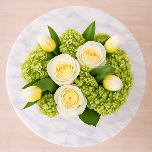 Top view of white roses, yellow tulips and green hydrangeas in a white ceramic planter