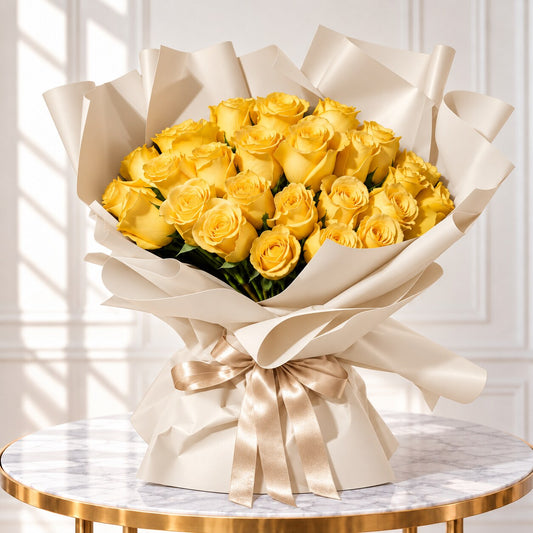 Yellow rose bouquet in ivory wrapping with a champagne ribbon on a white marble table