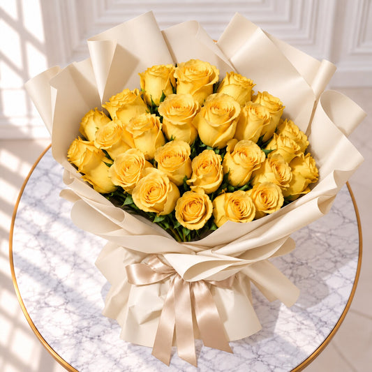 Yellow roses in ivory wrapping with a champagne bow on a gold-rimmed marble table