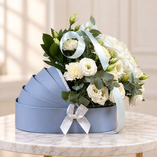 Baby boy flower arrangement in a blue bassinet with white blooms and eucalyptus