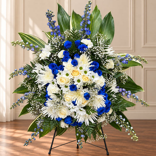 Blue funeral standing spray with royal blue roses, white chrysanthemums and delphinium on an easel