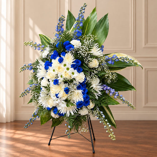 Royal blue roses and white memorial flowers in a handcrafted standing tribute by Amarilis Flowers