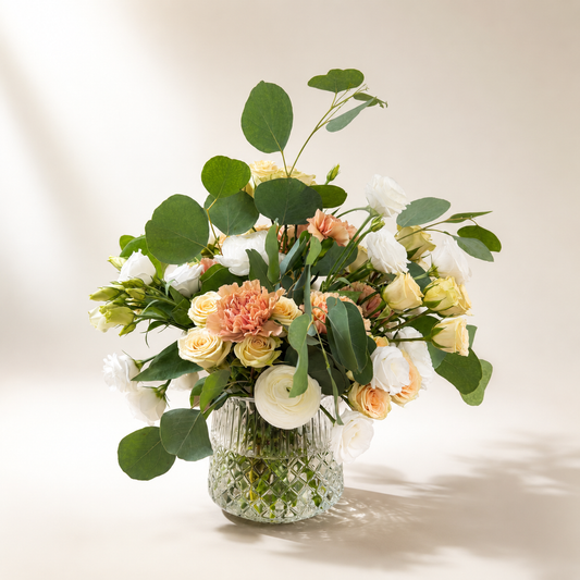 Champagne rose flower arrangement with blush blooms and eucalyptus in a textured glass vase