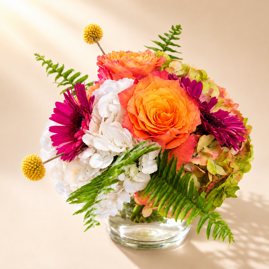 Colorful floral centerpiece Toronto featuring orange roses, gerbera daisies, hydrangeas, and fresh seasonal flowers by Amarilis Flowers.