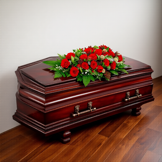Funeral flowers Toronto featuring red roses and lush greenery on casket