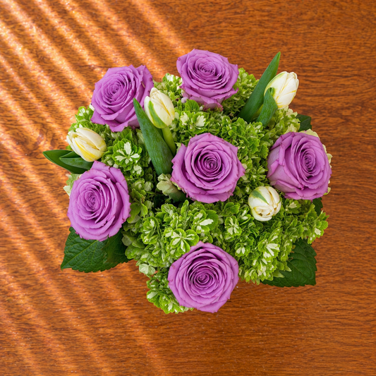 Bouquet of purple and white roses on a wooden surface