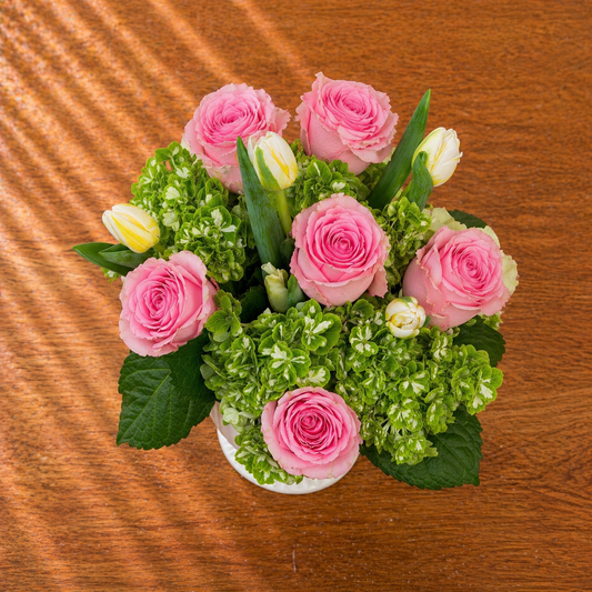 Bouquet of pink roses and green hydrangeas on a wooden surface