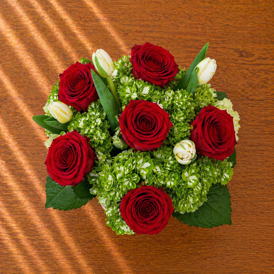 Bouquet of red roses and green foliage on a wooden surface