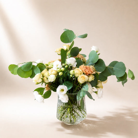 Garden style flower arrangement featuring champagne roses and fresh eucalyptus