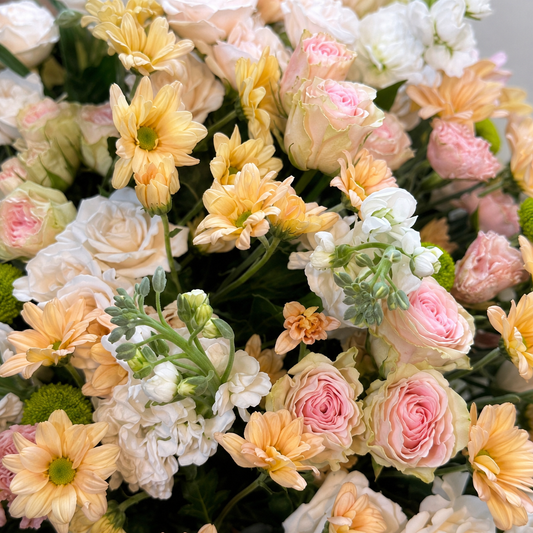 Close-up of blush and peach roses, white chrysanthemums and green accents in Gentle Farewell.