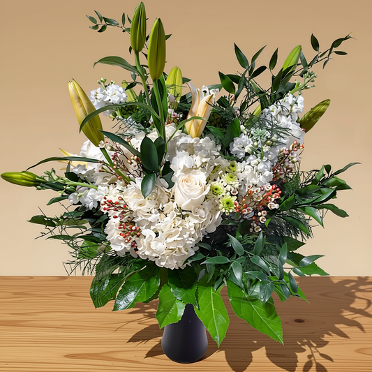 Hydrangea and rose flower arrangement displayed in a clear glass vase