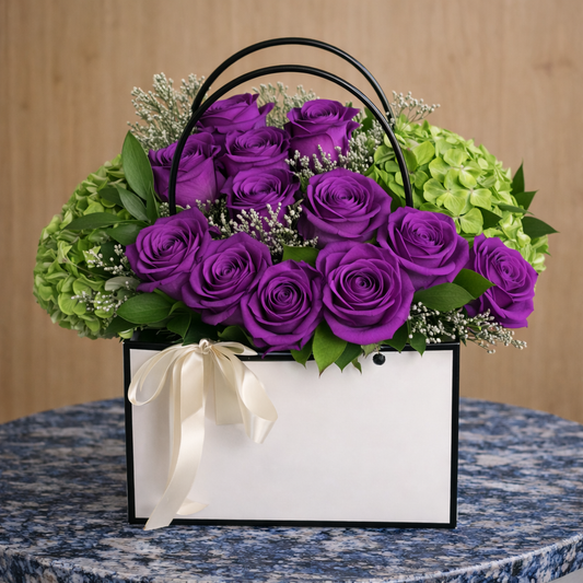 Basket of purple roses and green hydrangeas with a white ribbon on a marble surface.