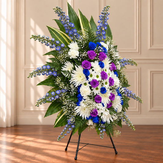 Purple and blue sympathy standing spray with white memorial flowers for a funeral service