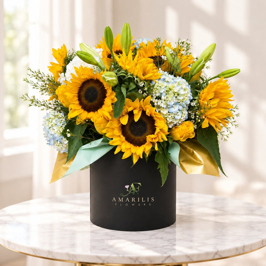 Sunlit Garden sunflower arrangement in Toronto with blue hydrangeas, yellow roses and a black floral box.