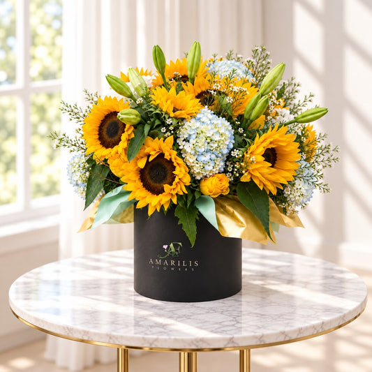 Angled view of the Sunlit Garden sunflower arrangement in a black box with gold and pale-blue accents