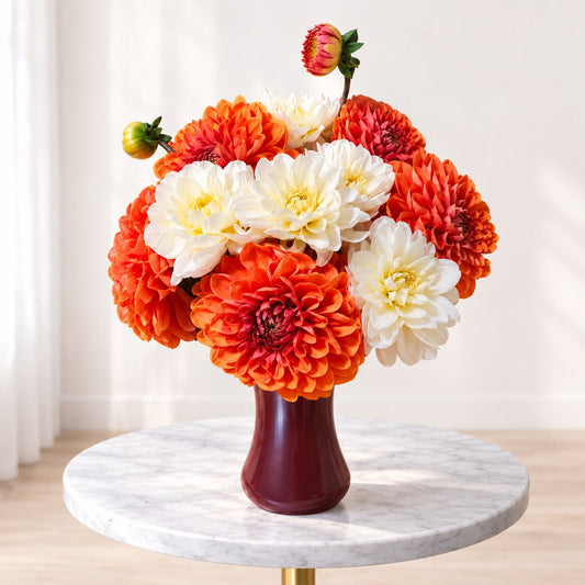 Thanksgiving flower arrangement with orange and ivory dahlias in a burgundy vase