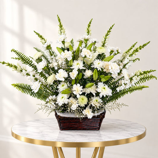 White funeral flower basket with lilies, roses, chrysanthemums and greenery arranged in natural wicker