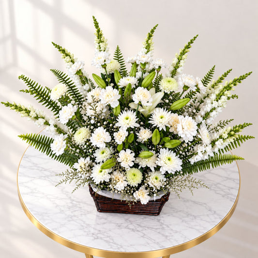 Side view of a white lily and rose funeral basket with carnations and layered greenery
